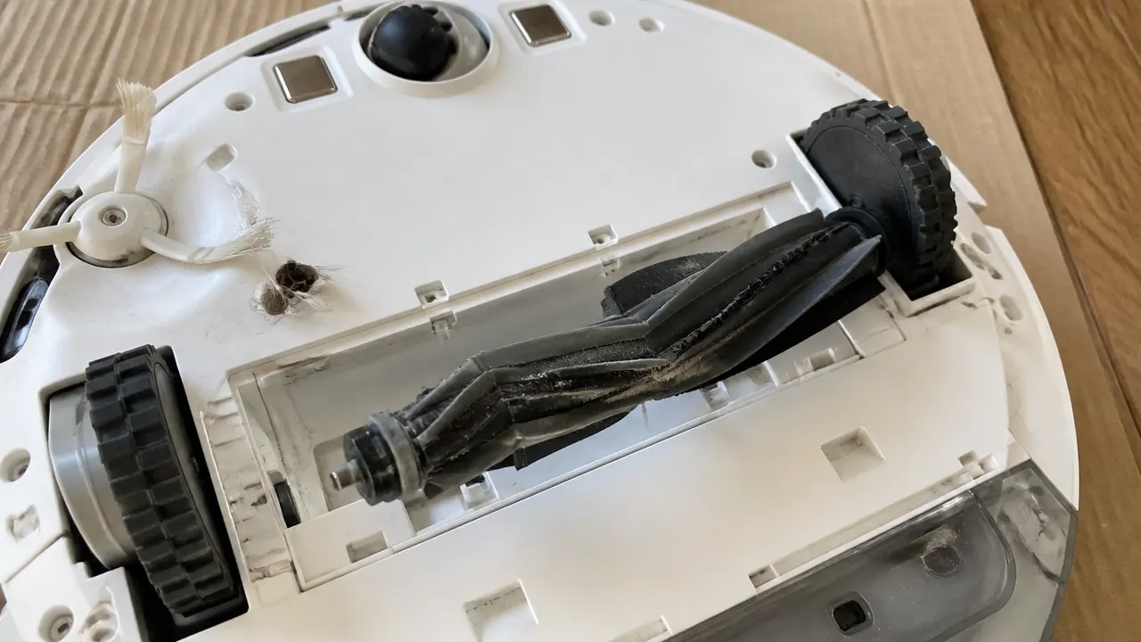 Dessous d'un robot aspirateur avec rouleau et brosse latérale